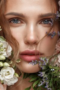 Beautiful woman with classic nude make-up, light hairstyle and flowers. Beauty face. Photo taken in studio