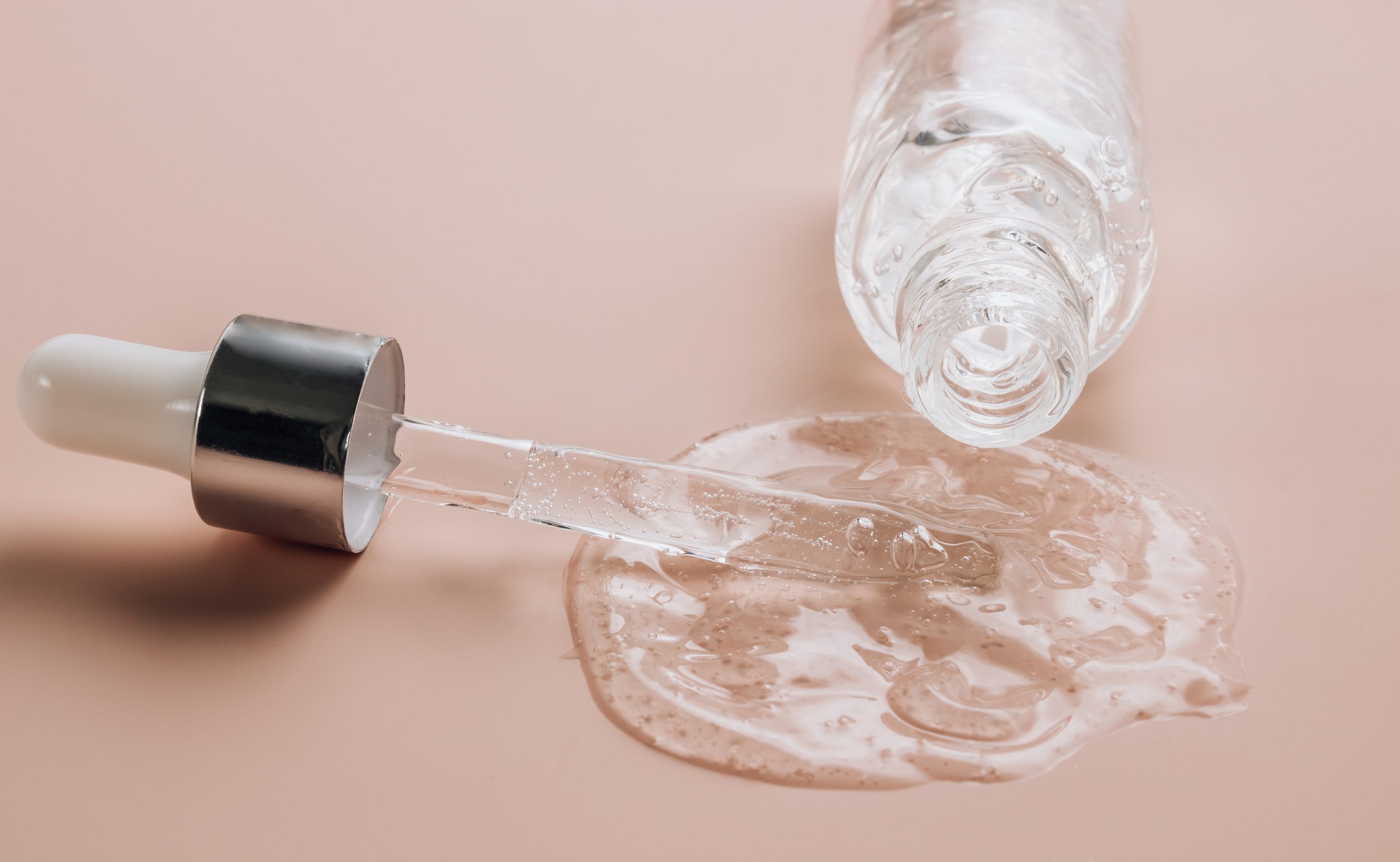 Hyaluronic acid on skin color background with oxygen bubbles. Bottle of hyaluronic acid on skin color background with oxygen bubbles. Selective focus