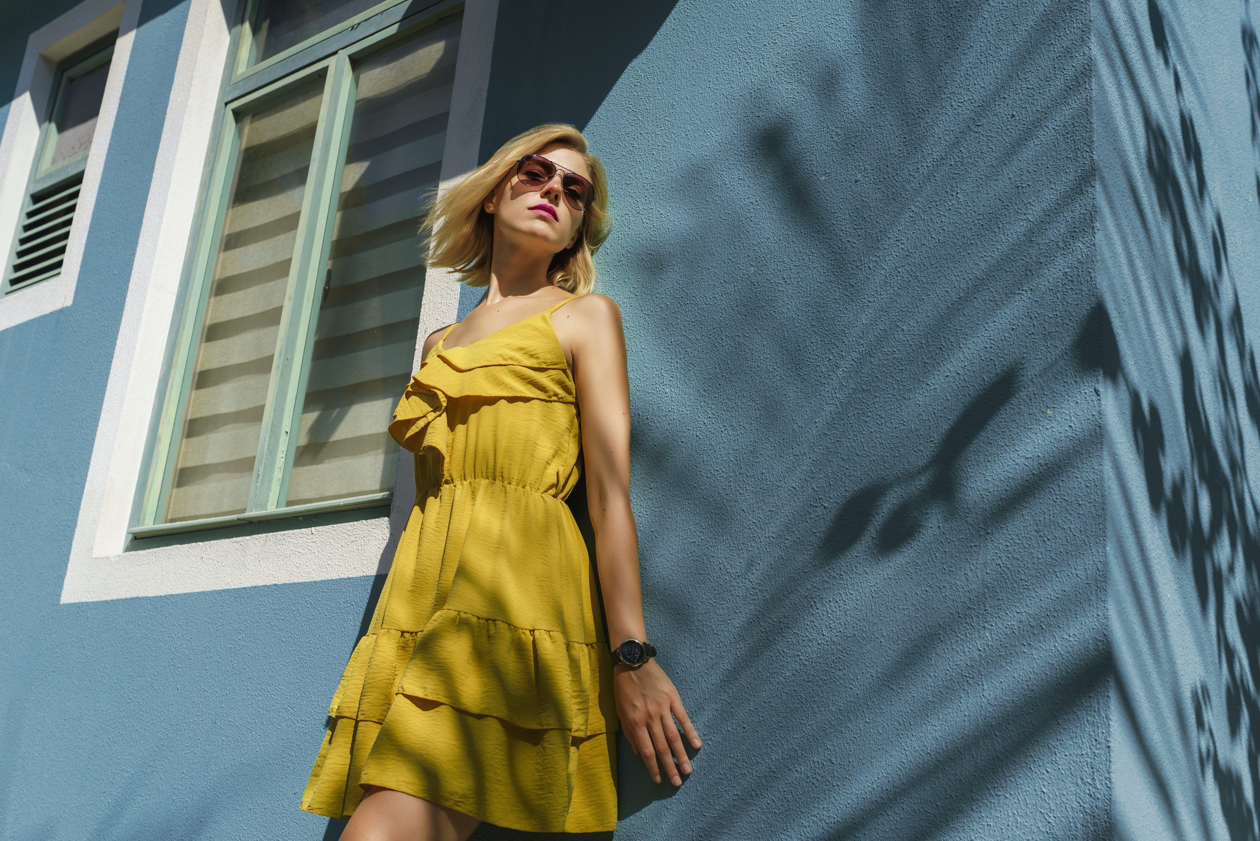 Portrait of woman smiling against wall with palm tree shade Portrait of woman smiling against wall with palm tree shade