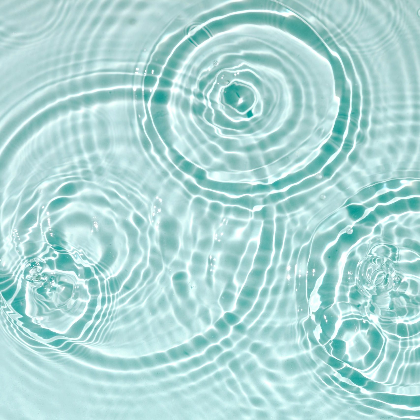 Water background. Blue water texture, blue mint water surface with rings and ripples. Spa concept background. Flat lay, top view, copy space.