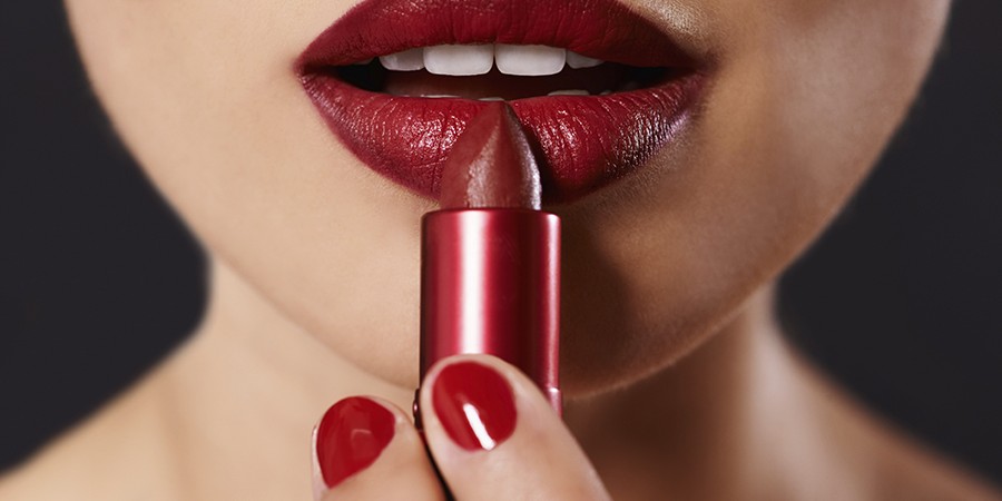 Closeup image of a woman applying lipstick