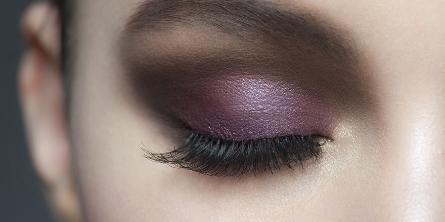 Closeup of beautiful woman eye with bright violet stylish makeup with long lashes