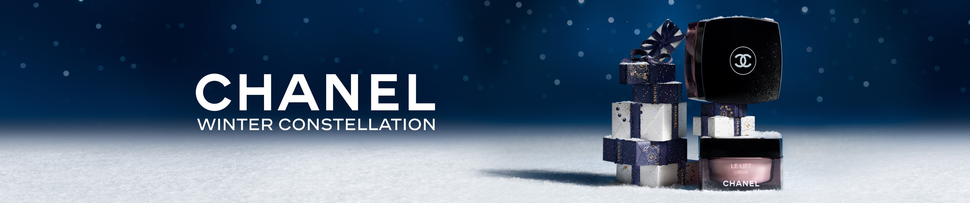 Chanel Winter Constellation – Le Lift Crème vor schneebedeckten Geschenkboxen mit Chanel-Logo vor sternenklarem Nachthimmel