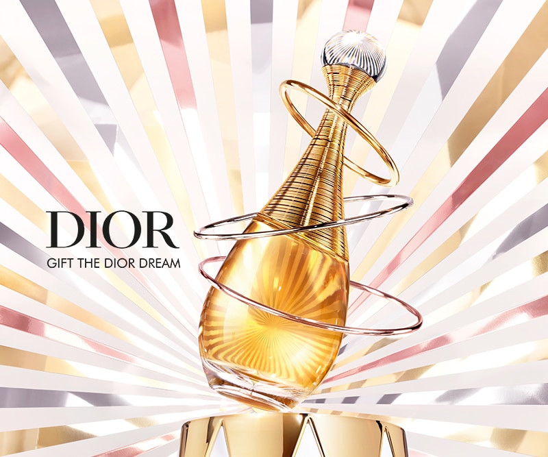 Dior J&apos;Adore-Parfümflakon mit goldenem Farbton und drei metallischen Spiralringen, vor einem strahlenden Hintergrund aus goldenen, silbernen und bronzenen Linien.