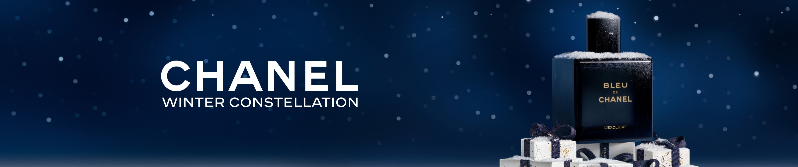 Chanel Winter Constellation – Bleu de Chanel Parfumflasche auf schneebedeckten Geschenkboxen mit dunkelblauen Schleifen vor sternenklarem Nachthimmel.