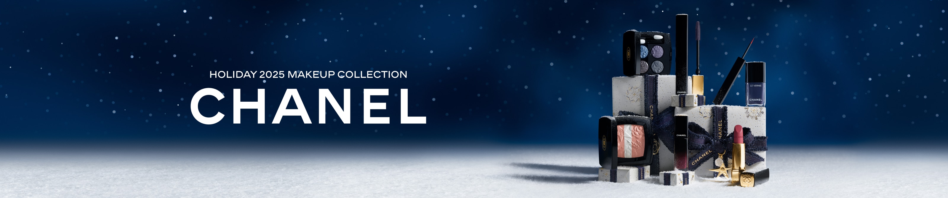 Chanel Holiday 2025 Makeup Collection – festlich präsentierte Make-up-Produkte in Schwarz und Gold auf schneebedeckten Geschenkboxen vor einem sternenklaren Nachthimmel