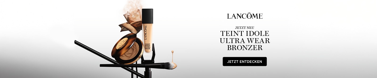 Lancôme Jetzt Neu Teint Idole Ultra Wear Bronzer - einer geöffneten Bronzer-Dose, einer Flasche Lancôme Teint Idole Flüssigfoundation und einem Make-up-Pinsel auf einem weiß-grauen Farbverlauf-Hintergrund mit einer roséfarbenen Blume im Nude-Ton.