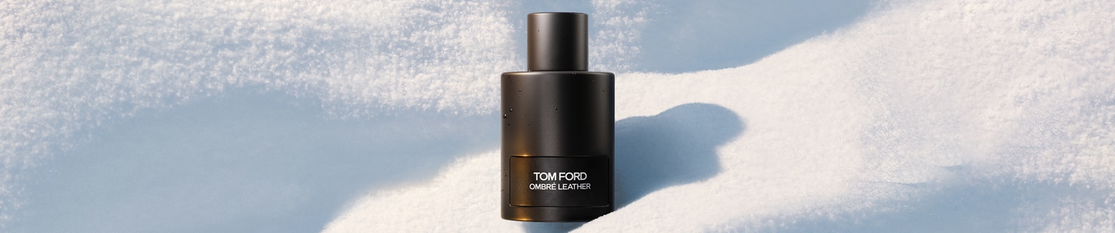 Eine schwarze Flasche des Parfums Tom Ford Ombré Leather vor einem Hintergrund aus Schnee.